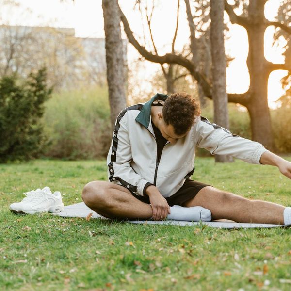 Smiling person stretching outdoors in a park at sunrise.