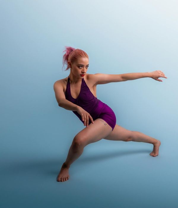 Woman performing a dynamic cardio movement in a minimalist studio.